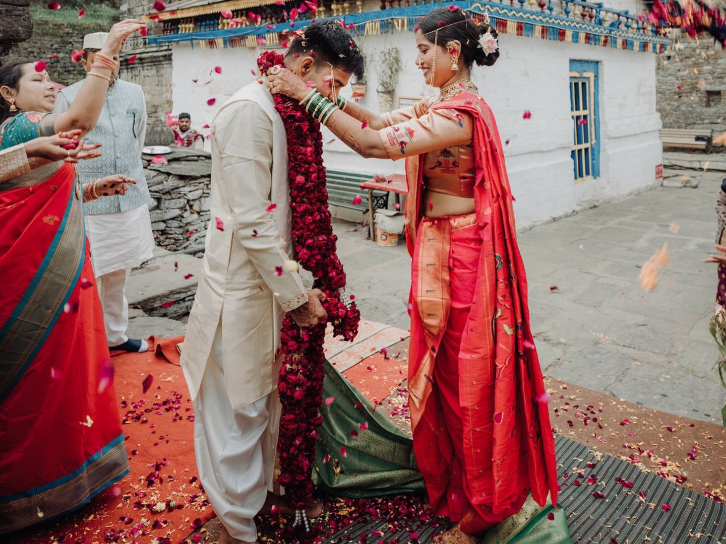 Joyful Indian bride and groom exchanging varmala garlands during their intimate traditional temple wedding ceremony, evoking the elegance of a marriage like Samantha Ruth Prabhu's.